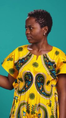 Stüdyoda sağa ya da sola işaret eden dikey video genç kadın işaret parmaklarını bir kenara kaldırıyor. Kendine güveni olan doğal bir insan geleneksel etnik giysiler giyer.