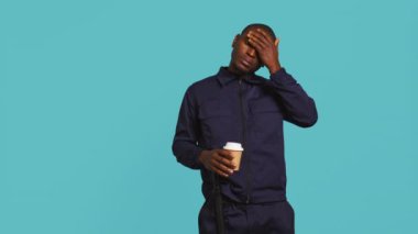 Yorgun bir güvenlik görevlisinin portresi kahve fincanı içerken mekâna neşe katıyor. Kafeinli içecek tüketen özel kolluk kuvvetleri çalışanı, stüdyo fon, kamera B