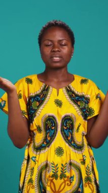 Stüdyoda Tanrı 'ya dua eden, dua eden ve mavi arka plana karşı iyi şeyler umut eden dikey video düşkünü genç yetişkin. Umutlu ruhani kız İsa 'ya inanıyor