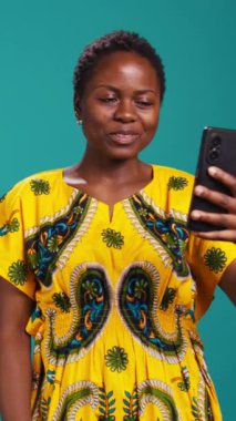 Vertical Video Friendly olumlu kadın akıllı telefonuyla online video görüşmeleri yapıyor, webcam 'e el sallıyor ve stüdyodaki arkadaşlarıyla sohbet ediyor. Gülümseyen tatlı kız gündelik bir konuşma yapıyor.