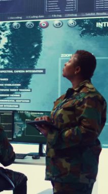Dikey Video Kadın yüksek teknoloji uzmanı büyük bir ekranda uydu CCTV görüntülemesini inceliyor, yeni bir ulusal güvenlik görevi için birlikleri hazırlıyor. Komutadaki kadın üsteğmen.