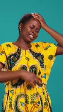 Dikey Video Kadını kendini çok yorgun hissediyor ve mavi arka planda esniyor. Stüdyoda uyku yoksunluğuyla uğraşan çok çalışan genç bir yetişkin. Yorgun ve bitkin bir yetişkin ve tükenmiş. Kamera B.