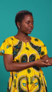 Stüdyoda sağa ya da sola işaret eden ve işaret parmaklarını sağa sola gösteren dikey, kendine güvenen kız. Genç doğal insan geleneksel Afrika kıyafetleri giyer.