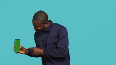 İşyerindeki neşeli güvenlik görevlisinin portresi mekanı denetlerken yeşil ekranlı telefonu gösteriyor. Neşeli özel polis memuru sunar akıllı telefon, stüdyo arkaplanı, kamera A