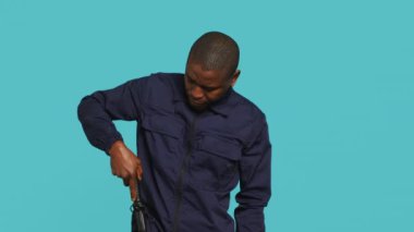 Güvenlik ajanının kemerden copu çıkartırken çekilmiş bir portresi. Atölyenin arka planında. Afrikalı Amerikalı muhafız, copu işaret ediyor, güvenlik ihlalleriyle ilgileniyor, kamera A