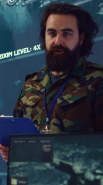 Dikey Video Piyade Birliği Komutanı, özel operasyonları yürütmek için birlikleri koordine ediyor, mürettebata ulusal güvenlik için görev detaylarını bildiriyor. Askeri komutan gerçek zamanlı gözetleme verileri üzerinde çalışıyor.