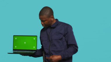 Koruma işinde çalışan ışıl ışıl bir güvenlik görevlisi sunar. Neşeli korumanın portresi izole bir ekran defteri, stüdyo arka planında izole edilmiş, kamera A