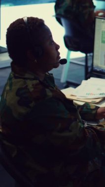 Dikey Videolu Kadın ordu subayı, düşman planları hakkında önemli bilgiler toplamak için GPS güvenlik kamerası görüntülerini kullanıyor. Operatör saha birliklerine destek sağlamak için bir uydu dünya haritasını inceliyor.