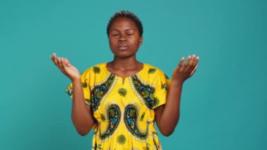 Dini iyimser kız stüdyoda iyi şans için Tanrı 'ya dua ediyor. Mavi arka plan için dua eden biri. Din ve maneviyata inanan genç bir kadın. Kamera A.