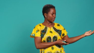 Stüdyoda sağa ya da sola işaret eden, işaret parmaklarıyla işaret eden kendine güvenen bir kız. Genç doğal insan geleneksel Afrika kıyafetleri giyer.
