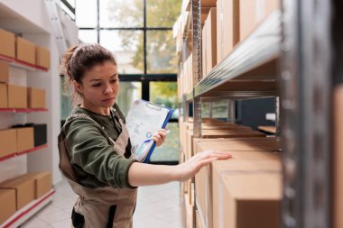 Depo müdürü karton kutuları kontrol ediyor, müşterilerin siparişlerini depoda hazırlıyor. Kafkas çalışanı depoda malzeme detaylarını içeren belgeleri tutuyor.