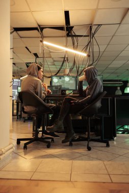 Genç hackerlar Truva virüsü programını sisteme sızmak için kodluyor bilişim uzmanları yasadışı güvenlik duvarı şifreleme programlıyorlar. İki siber suçlu gece geç saatlerde kötü niyetli yazılım geliştiriyor..