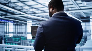 Yıllık bakım kontrolü yapan programcı, veri merkezi elektronik yaşam süresini uzatmak için dizüstü bilgisayar kullanıyor. Not defteri, kamera B kullanarak sunucu çiftliği izleme sunucusu altyapısında bilişim uzmanı