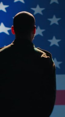 Dikey video Amerikan askeri komuta merkezinde ABD bayrağına el sallayarak saygı gösteriyor. Birleşik Devletler Silahlı Kuvvetleri 'nde görev yapan, vatansever bir askeri birlik.