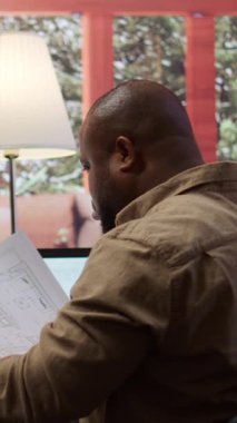 Dikey Video İşadamı yeni ofis alanı planının mimari planlarını analiz ediyor, yeni bir başlangıç arıyor. Girişimci bir ofis avı, iş geliştirme ve strateji planlaması yürütüyor