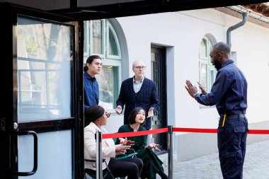 Pazarlık peşinde koşan müşteriler, Kara Cuma günü alışveriş merkezinin kapısının açılmasını bekliyor, sabah dışarıda sıraya girdiler. Mağazada satışları beklerken müşteriler güvenlik görevlisiyle tartışıyor.