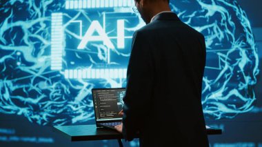 Yüksek teknoloji ürünü atölyede dizüstü bilgisayar kullanan yapay zeka sistem yöneticisi. Yapay zeka teknolojisi kullanarak görevleri otomatikleştirmek için bilgisayar üzerinde çalışan adam, kamera A