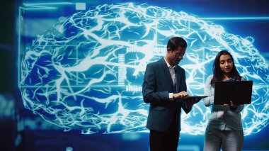 Bilgisayar ve tablet üzerinde görevleri çözen, yapay zeka programlama senaryoları çalıştıran bilişim departmanı meslektaşları. Yapay zeka uygulamaları geliştirmek için beyin fırtınası yapan mühendisler ekibi, kamera B