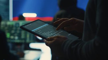 Person uses tablet in governmental cyber security room working under the Russian flag. Making cyber threats, hacking systems to gain unauthorized access, and spreading fake news. Close up. Camera A. clipart