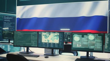 Büyük ekranda Rus bayrağı dalgalanan, siber terörizm ve propaganda tehdidini gösteren boş otokrasi siber savunma odası. Rus hackerların sahte haberler yayma faaliyetleri. Kamera B.