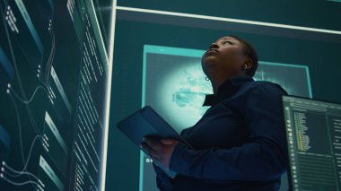 Siber istihbarat uzmanı, siber savunma ve siber saldırılara karşı korunma üzerine çalışan bir devlet kurumundaki büyük ekrandaki verileri inceliyor. Melez savaşında özel bilgi. Kamera B.