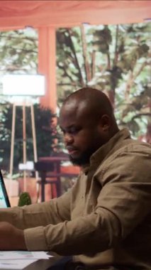 Vertical Video Young 'ın serbest çalışan işadamı internet üzerinden alışveriş yapıyor ve ev ofisinde elektronik bankacılık ödemeleri yapıyor. Freelancer uzaktan kumandayla bir şeyler satın alıyor.