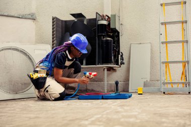 Becerikli tamirci yıllık konsantratör bakımına hazırlanıyor. Hasarlı klima iç parçalarını tamir etmek için gerekli profesyonel teçhizatla dolu alet çantası açan eğitimli bir tamirci.