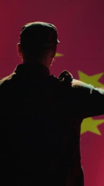 Çin ordusunun dikey video mensubu komuta merkezinde Çin bayrağına el sallayarak saygı gösteriyor. Üniformalı askeri birlik Çin Komünist Partisi 'ne hizmet ediyor.