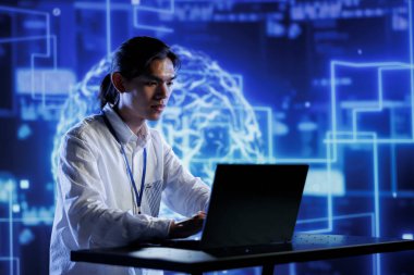 Veri merkezinde Asyalı yönetici yapay zeka kullanarak insan beynini kendi kendini öğrenme algoritmalarıyla simule ediyor. Çalışanların elinde dizüstü bilgisayar var, yapay zeka derin sinir ağlarıyla çalışıyorlar.