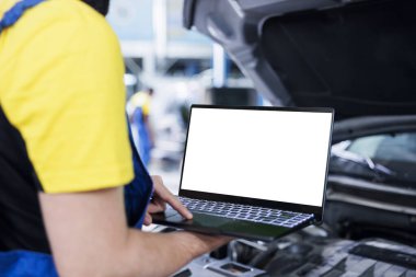 Garajda deneyimli bir tamirci. Araba bakımını yaparken kontrol listesini takip etmek için dizüstü bilgisayar kullanıyor. Otomobil tamir atölyesindeki çalışanlar, izole ekran cihazının yardımıyla aracın kontrolünü yapıyor