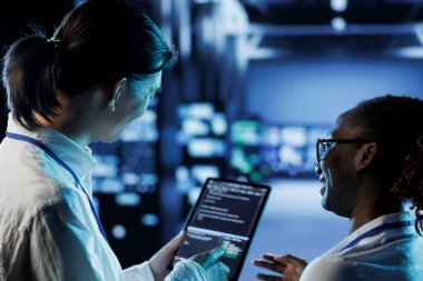 Mühendis ve Afrikalı Amerikalı meslektaşım sunucu odasında güvenlik duvarı sistemi kuruyor. Veri merkezi donanımlarını yükseltmek için tablet üzerinde kod çalıştıran erkek ve kadın iş yükü talep ediyorlar