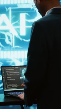 Yüksek teknoloji fütüristik çalışma alanında dizüstü bilgisayar kullanan dikey video yapay zeka sistemi yöneticisi. Yapay zeka teknolojisi kullanarak görevleri otomatikleştirmek için bilgisayar üzerinde çalışan adam, kamera A
