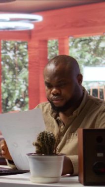 Dikey Video Girişimcisi ev ofisindeki iş analizlerini not alıyor ve yönetiyor, bir dizüstü bilgisayardaki ekonomik eğilimleri analiz ediyor. Serbest çalışan danışman uzaktan çalışmanın etkinliğini gösteriyor.