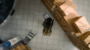 Afro-Amerikan lojistik şefinin depodaki hasarlar için karton kutuları incelemesi. Depo müfettişi stokların ve envanterlerin iyi organize edildiğinden emin oluyor.