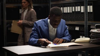 Afrika kökenli Amerikalı müfettiş soruşturmayı yürütür, kanıt toplar ve dava detaylarını inceler. Özel dedektifin yakın plan fotoğrafı. Gizli şüpheli profili ve bilgileri özenle analiz ediyor..