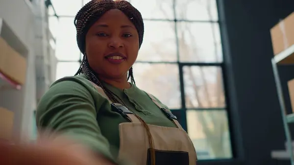 stock image African american warehouse employee using selfie smartphone camera to participate in online videocall with management executives. Worker in teleconference meeting with distribution center managers