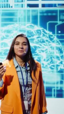 Vertical Video Tech başlangıç yöneticileri teknoloji zirvesi sırasında en son yapay zeka hizmetlerini sunuyorlar. İş adamları, yapay zeka ve kamera B ile ilgilenen yatırımcılara sunum yapmak için mikrofonu kullanıyorlar.