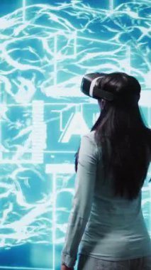VR kulaklık takan dikey video geliştirici insan beyni simülasyonunun hologramına bakıyor. Yapay Zeka görselleştirmesi ile etkileşen programcı makine öğrenme algoritmalarını gösterir