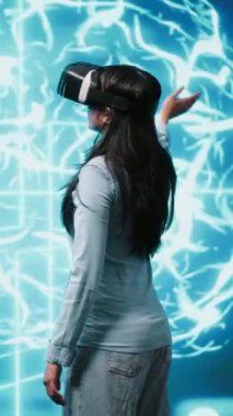 VR kulaklık takan dikey video geliştirici insan beyni simülasyonunun hologramına bakıyor. Yapay Zeka görselleştirmesi ile etkileşen programcı makine öğrenme algoritmalarını gösterir
