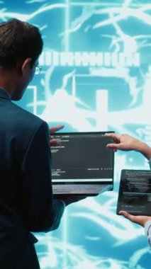 Dikey video çalışanları beyin fırtınası yapıyor, yapay zeka sinir ağlarını onarmak için cihazlar kullanıyorlar. Yüksek teknolojili çalışma alanı meslektaşları yapay zeka sistemini kullanarak işleme ve iletime yardımcı oluyorlar.