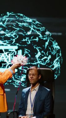 Dikey video şirketi CEO 'su en son AI EEG kulaklık ürününü piyasaya sürmek için zirveyi platform olarak kullanıyor. Nörobilimci, suni tedaviyle ilgilenen iş adamlarının önünde forumda gösteri yapıyor.