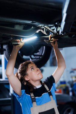 Araba servisindeki bilgili tamirci tekerlekleri değiştirdikten sonra cıvataları sıkmak için kerpeten kullanıyor. Becerikli oto tamircisi kadın müşteri otomobilini tamir etmek için profesyonel aletler kullanıyor.