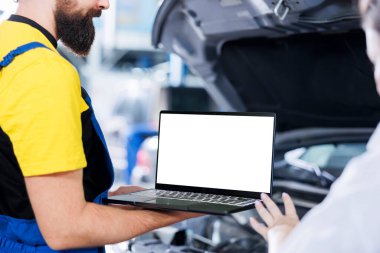 Garajda sertifikalı bir mühendis, arabanın bakımını yaparken kontrol listesini takip etmek için dizüstü bilgisayar kullanıyor. Otomobil tamir atölyesindeki usta işçiler, izole ekran cihazının yardımıyla aracın kontrolünü yapıyor