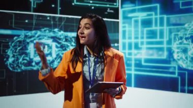 Teknoloji forumunda sunum yapan bir konuşmacı, gelişmekte olan yapay zeka teknolojilerinin şirketlerin iş gücünü olumlu yönde artırabileceğini keşfediyor. Hintli kadın yapay zeka çözümleri üretiyor