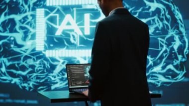Yüksek teknoloji ürünü atölyede dizüstü bilgisayar kullanan yapay zeka sistem yöneticisi. Yapay zeka teknolojisi kullanarak görevleri otomatikleştirmek için bilgisayar üzerinde çalışan adam, kamera A