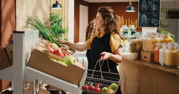 stock image Diligent eco friendly grocery store employee restocking shelves with fresh fruits and vegetables. Local neighborhood supermarket storekeeper adding organic farm grown food on display