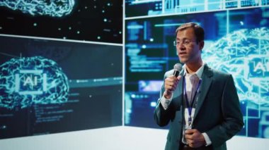 Sunucu, yapay zeka ve bilişsel bilgisayar alanındaki son gelişmelerden, kamera B 'den bilgi paylaşan bilişim uzmanlarını bir araya getiren yapay zeka konferansındaki izleyicilerle konuşuyor.