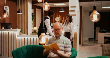 Otelde turistleri karşılayan çeşitli ekipler, beş yıldızlı tatil inzivasında kontrol işlemlerine yardım ediyorlar. Emekli bir kadın için valiz taşıyan bellboy mükemmel kapıcı hizmeti sunuyor..