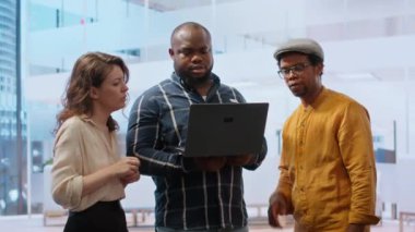 Emlakçı müşterilere yeni bir ofis binası sunuyor. Mülk turu sırasında tablet kullanarak detaylı planları tartışıyor. Potansiyel bir yatırım fırsatı. Kamera B.