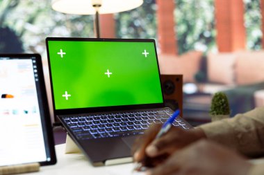 İşyeri sahibi yeşil ekranın yanındaki yıllık raporlar için notlar yazıyor, istatistikleri ve mali analizleri gözden geçiriyor. Girişimci, girişimin kar ve fonlarını artırıyor.